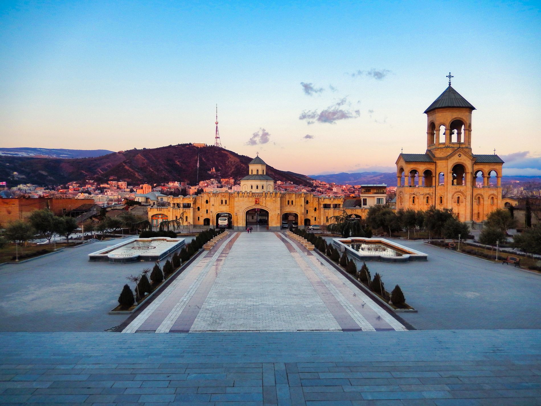 Illuminated gates of Sameba Cathedral in the evening — glowing arch and warm lighting create serene atmosphere in central Tbilisi