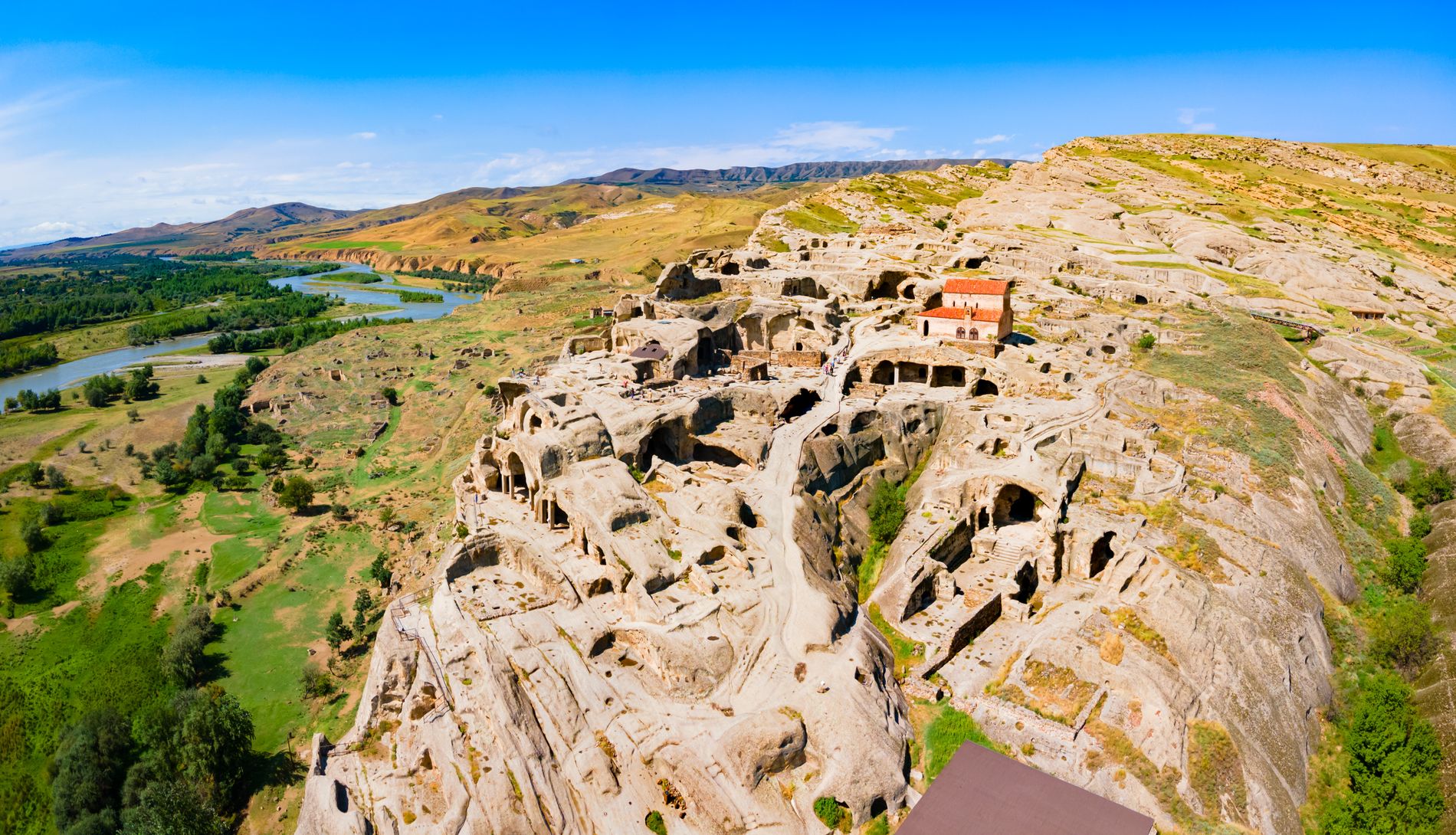 Aerial view of Uplistsikhe — ancient rock-cut city in central Georgia with tunnels, temples, and open-air chambers carved into sandstone cliffs