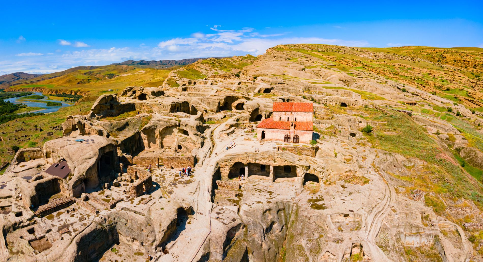 Aerial view of Uplistsikhe — ancient rock-cut city in central Georgia with tunnels, temples, and open-air chambers carved into sandstone cliffs