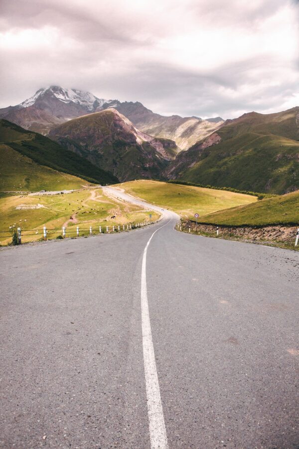 Winding mountain road near Gergeti Church — scenic drive with panoramic views of the Kazbegi range and Stepantsminda valley