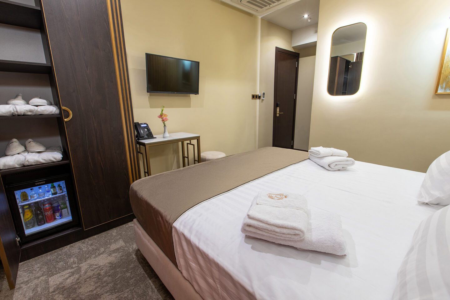 Full view of Deluxe Flex room at Bellevue Boutique Hotel — premium bed, soft towels, desk, flat-screen TV and minibar setup