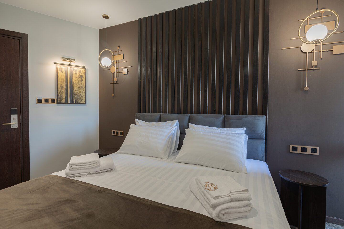 Stylish double bed in a boutique hotel room in Tbilisi — soft lighting, wall panel above the bed and built-in bedside lamps