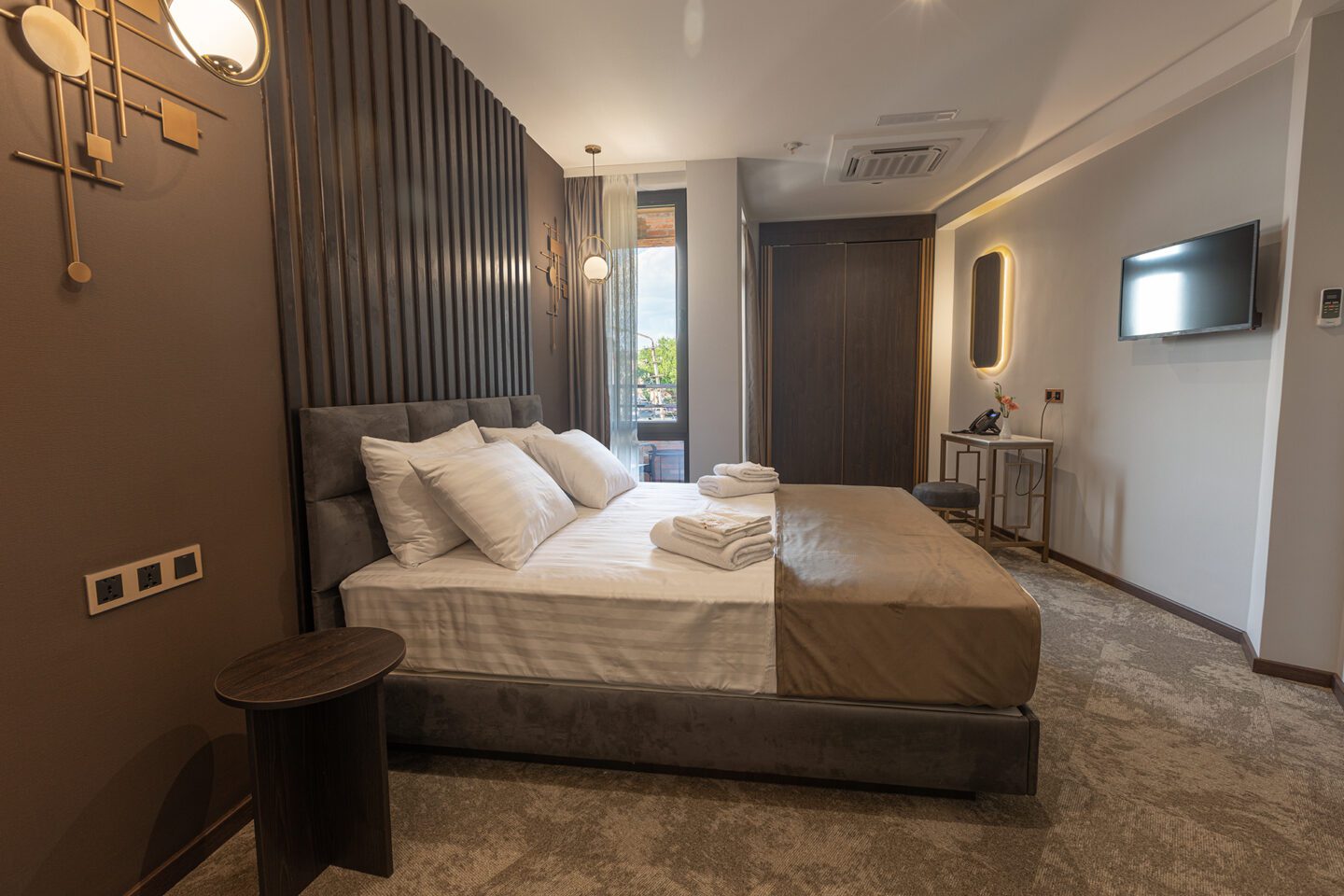 Deluxe double or twin room at Bellevue Boutique Hotel in Tbilisi, Georgia — bed, work desk, mirror, TV, and wardrobe with balcony light