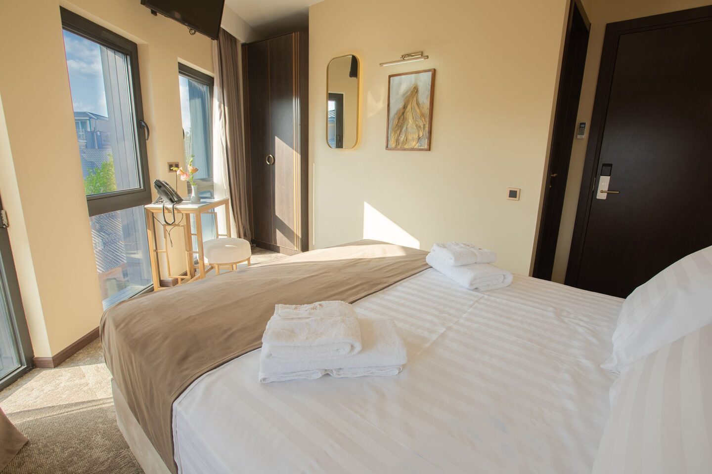 Spacious premier room at Bellevue Boutique Hotel — extra-large bed, smart TV, desk, wardrobe and full-height balcony windows in Tbilisi