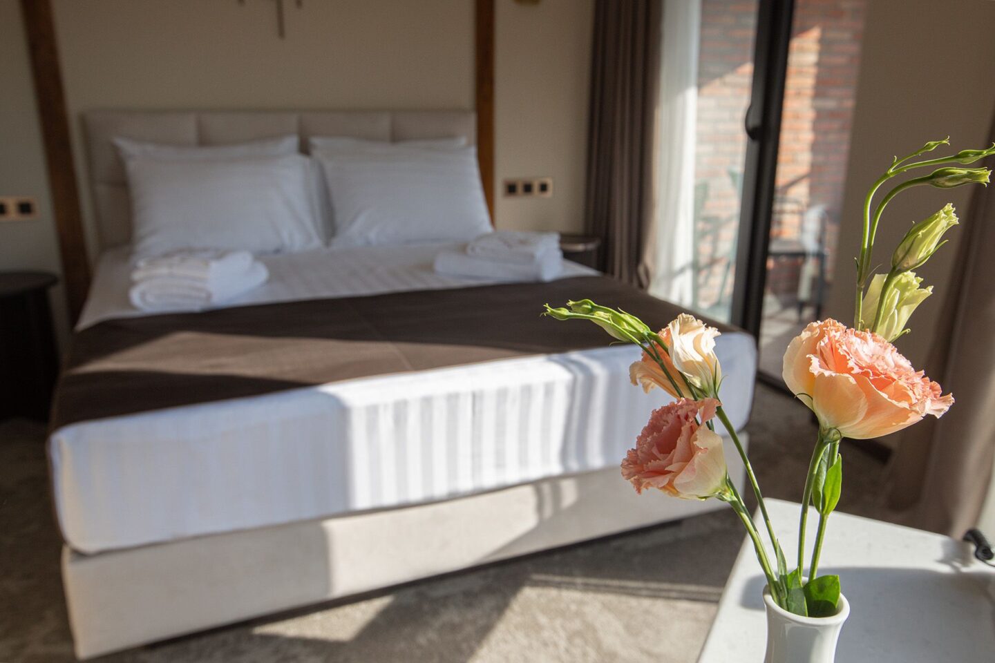 Cozy bed in natural daylight, premium cotton linen and flowers delivered to the room — serene atmosphere at Bellevue Boutique Hotel